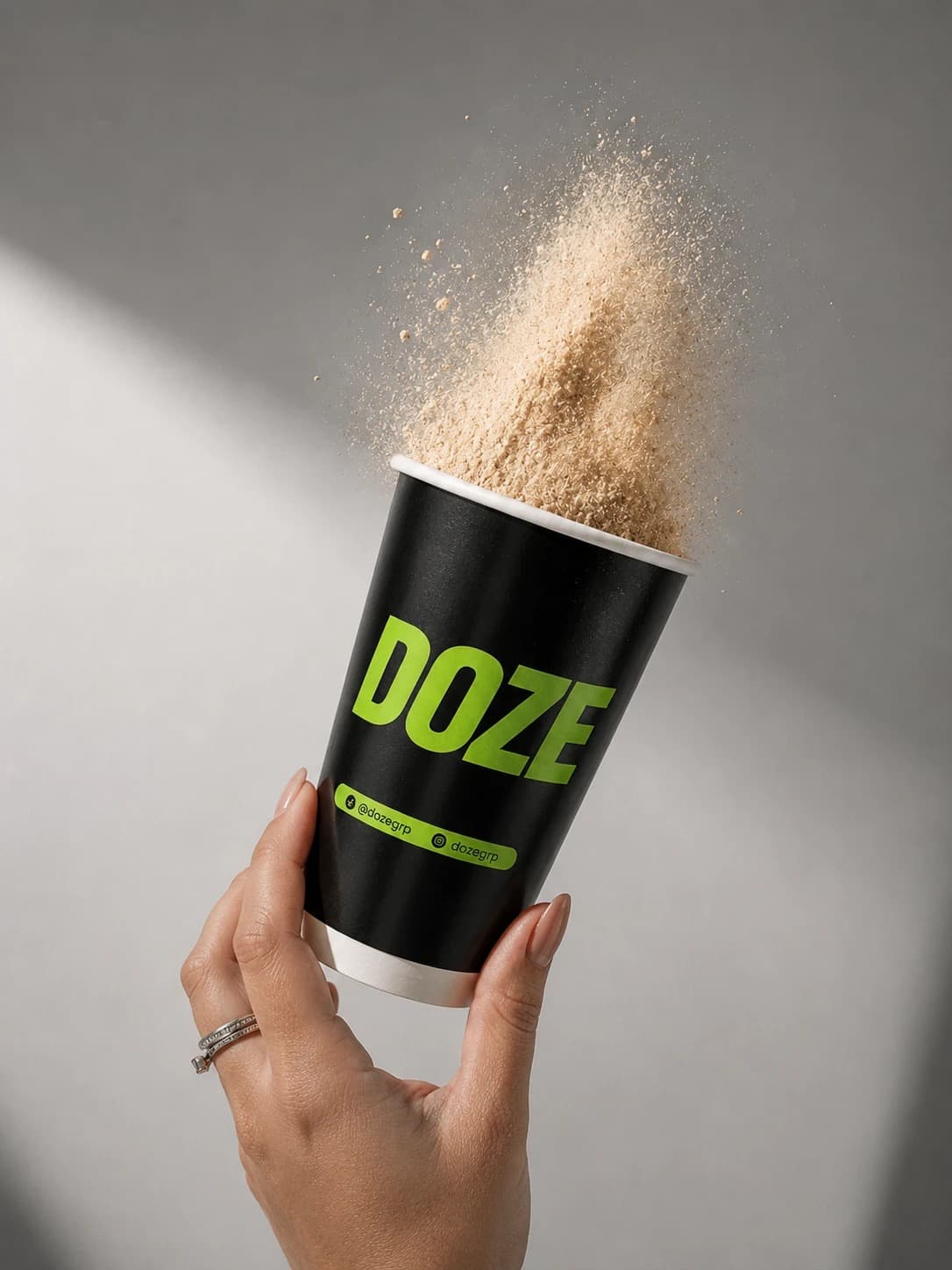 Mano sosteniendo un vaso negro de DOZE con polvo de proteína en el aire