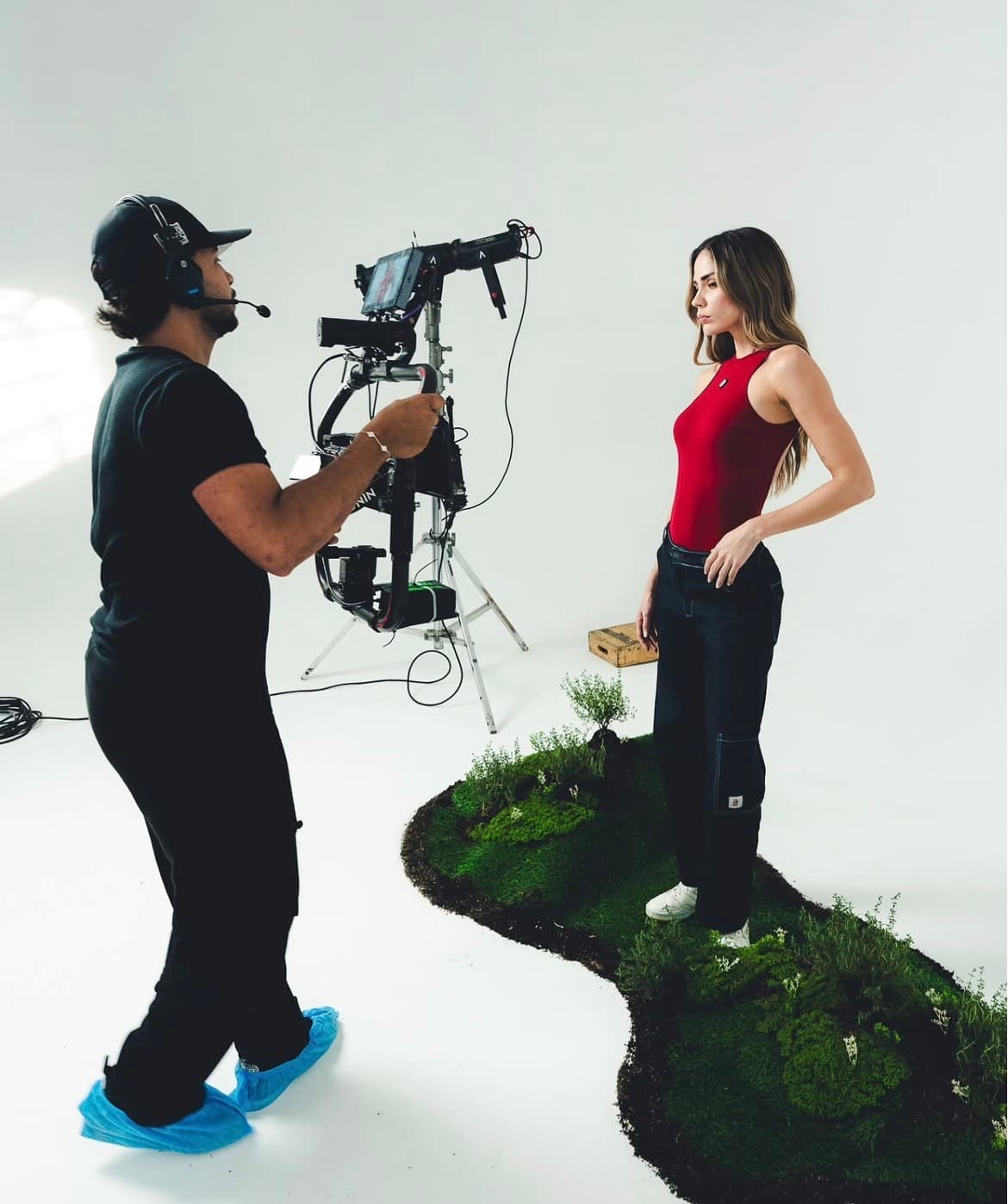 Operador con gimbal frente a una modelo con body rojo sobre una isla de musgo