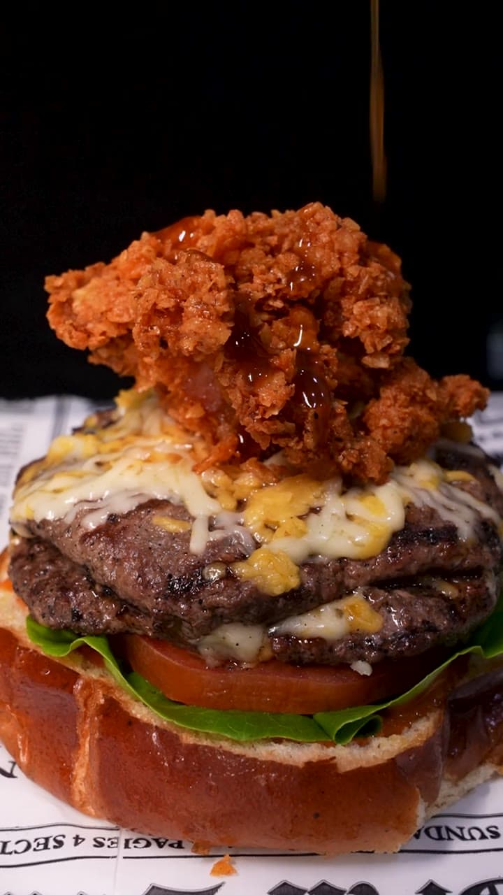 Hamburguesa con pollo crocante y queso sobre papel periódico de The Grill Station