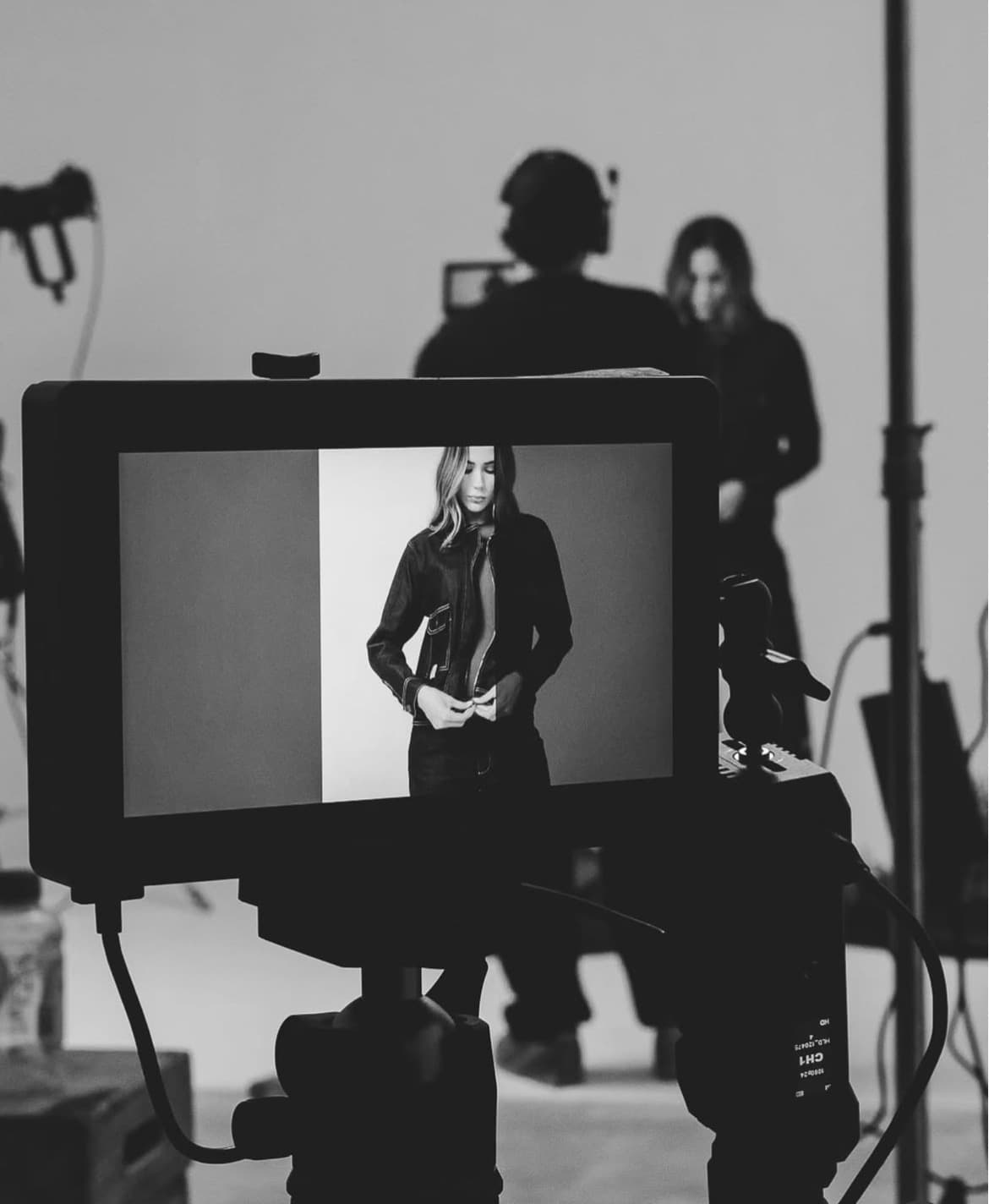 Monitor en blanco y negro mostrando a una modelo con chaqueta en un set desenfocado